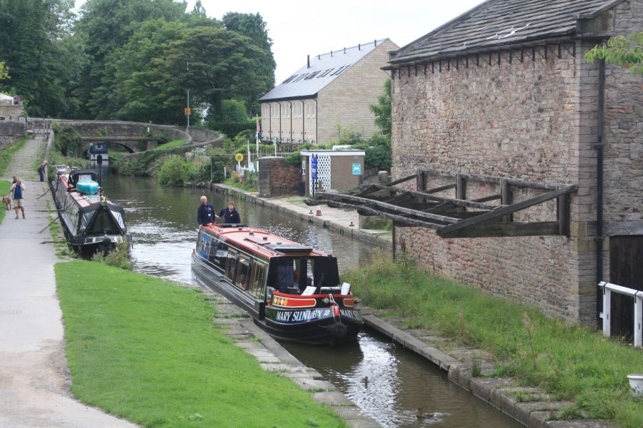 Narrowboat passing Marple Wharf and snake bridge on the Macclesfield Canal
