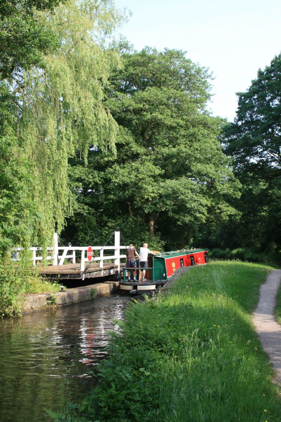 Narrowboat passing through swingbridge on Macclesfield Canal near Lyme Green